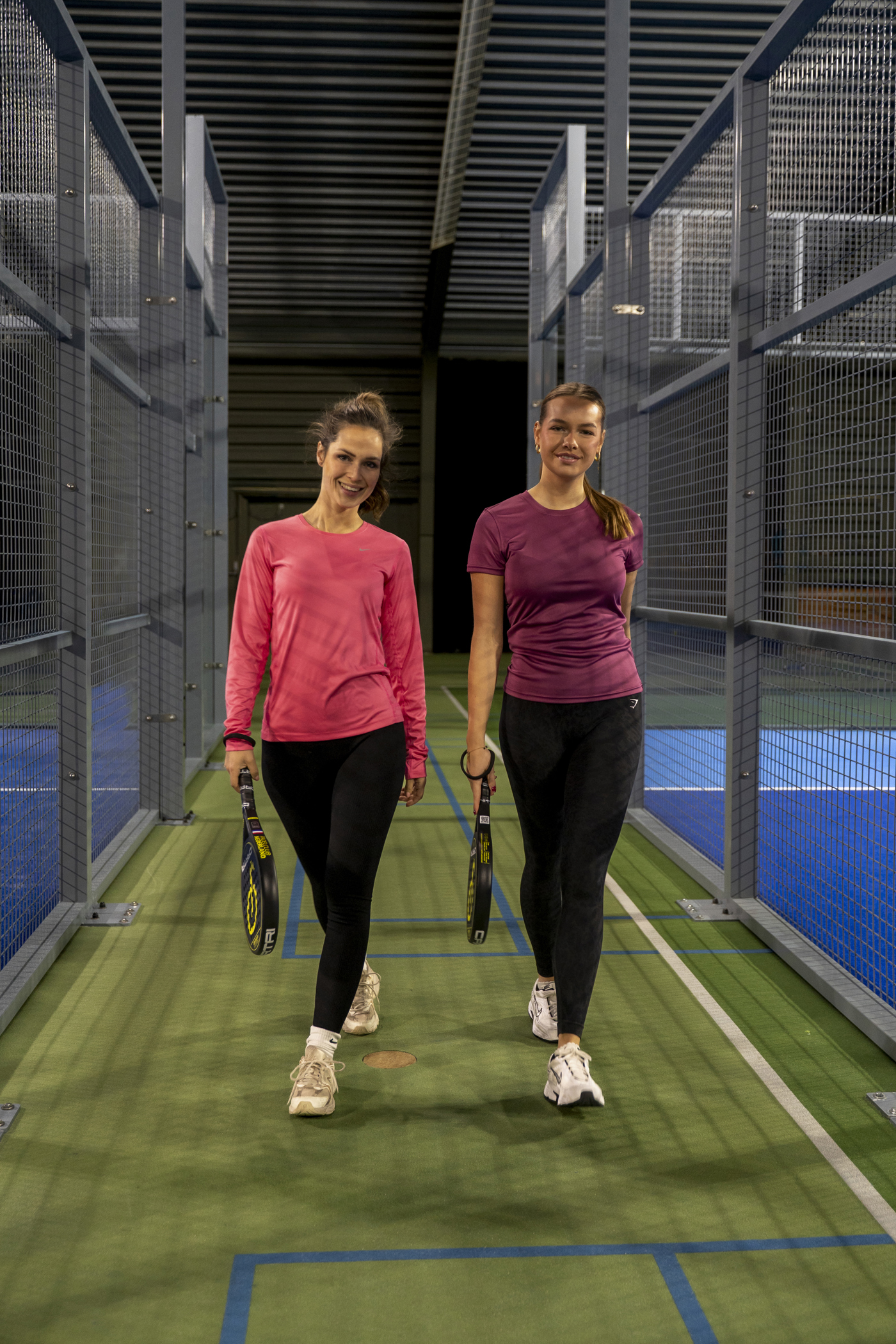 Twee vrouwelijke padelspelers zitten ontspannen op de padelbaan na een potje padel bij Padelclub Nederland Zuidbroek.