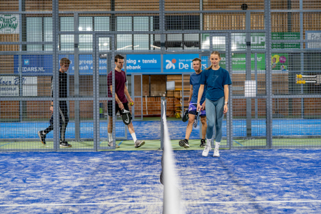 Vier padelspelers die samen naar de padelbaan lopen op een vast moment via een baancontract bij Padelclub Nederland