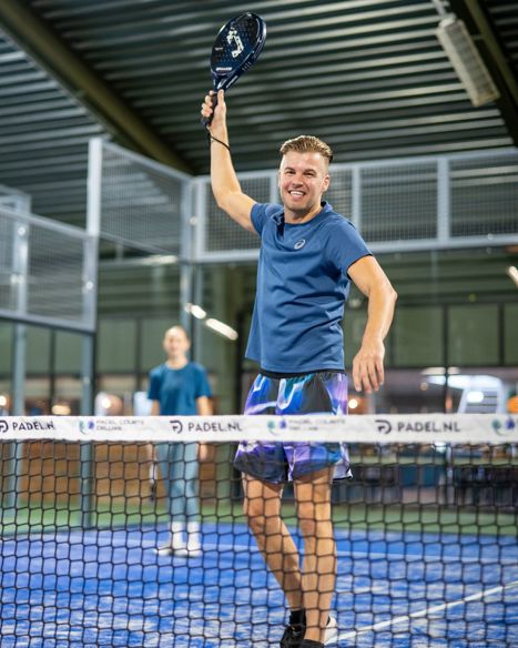 Padel speler die bal speelt op een padel single baan bij Padelclub Nederland