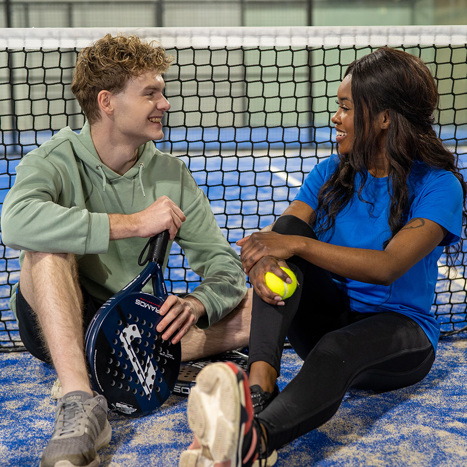 Twee padelspelers zitten voor het net op een indoor padelbaan vlakbij Zwolle.